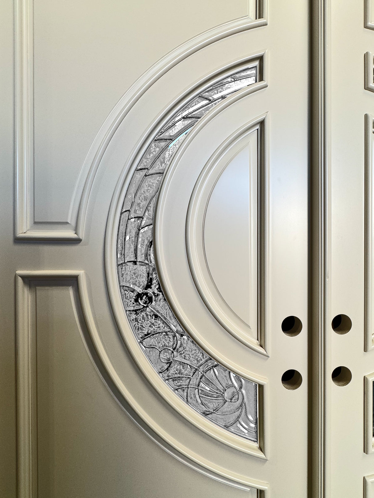 Detailed close-up of crescent-shaped glass panels on white entry door highlighting design and texture