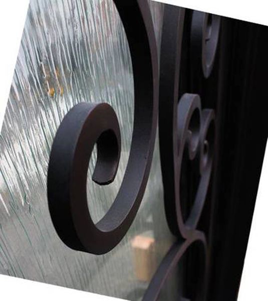 Close-up detail of textured rain glass panel on black iron front door showing privacy glass design and steel framing