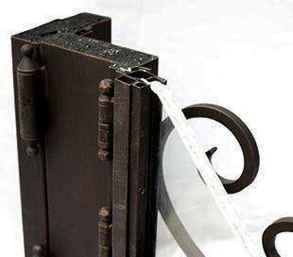 Detailed close-up of upper section of iron entry door showing vertical glass panel integration within steel frame